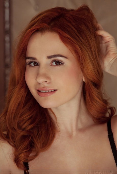Sexy redhead Nicole La Cray lifts her long legs high to bare her shaved pussy