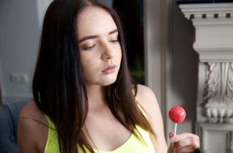 Young brunette Phonexia holds a sucker while stripping totally naked