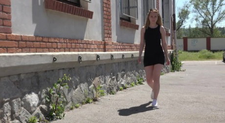 Blonde girl squats for a pee in a laneway while wearing a black dress