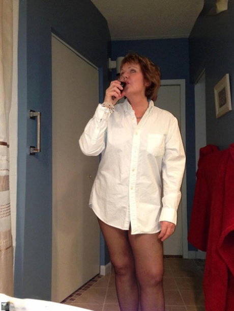 Older amateur Busty Bliss raises a toast before showing her painted toenails