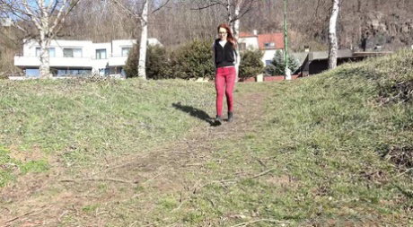 Redheaded girl Sandra pees on a path while walking near the water