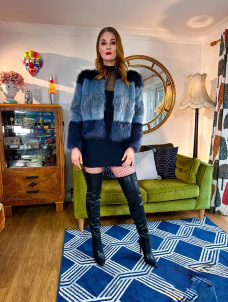 Sexy redhead models a fur coat and black miniskirt in thigh-high boots