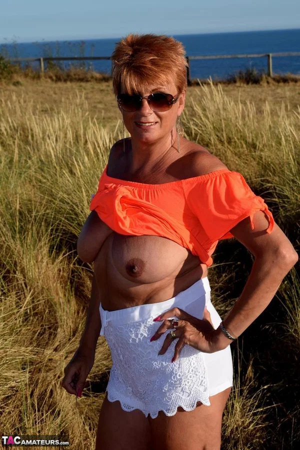 Older redhead Dimonty uncovers her natural tits not too far from the ocean  - Mature, Saggy Tits, Short Hair, Shorts, Redhead, Amateur, Glasses, Outdoor, Clothed, Legs  - Photo 15