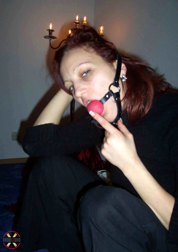 Clothed redhead affixes a ball gag while sitting afore a St Andrew's Cross  - Bondage, Clothed, BDSM, Non Nude  - Photo 13