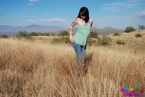 Tattooed brunette B4rbi3 undresses while standing in an expansive field  - Teen, Outdoor, Jeans, Tattoo, Undressing, Big Tits, Natural Tits, Skirt, Clothed, Ass  - Photo 3