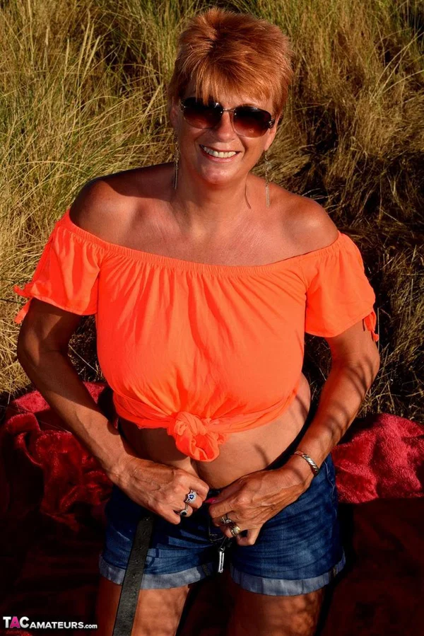 Older redhead Dimonty uncovers her natural tits not too far from the ocean  - Mature, Saggy Tits, Short Hair, Shorts, Redhead, Amateur, Glasses, Outdoor, Clothed, Legs  - Photo 11