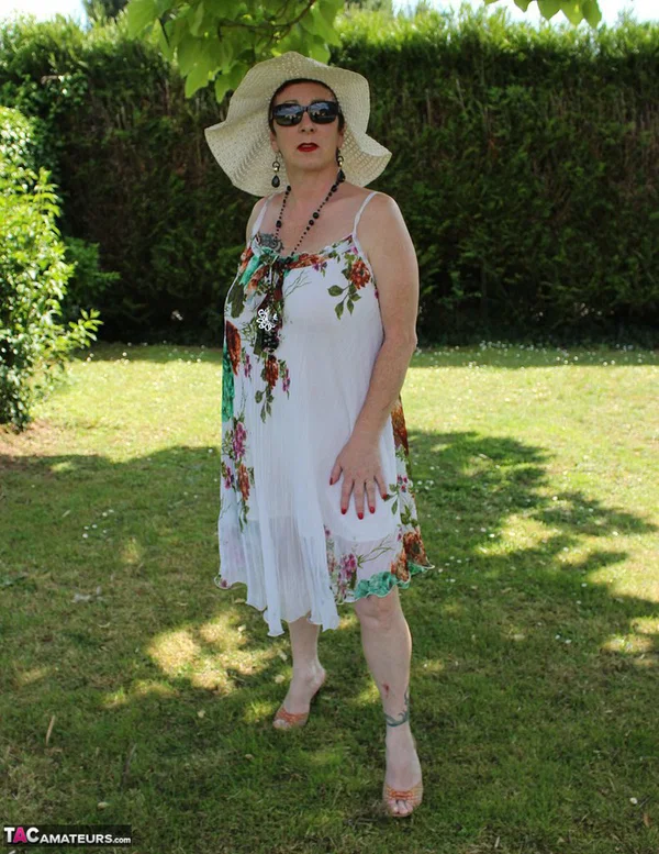 Mature amateur Mary Bitch pulls down her thong on a lawn in a sun hat  - Mature, Outdoor, Amateur, Glasses, Clothed, High Heels, Hairy, Pussy, Ass, Tattoo  - Photo 1