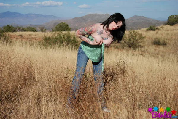 Tattooed brunette B4rbi3 undresses while standing in an expansive field  - Teen, Outdoor, Jeans, Tattoo, Undressing, Big Tits, Natural Tits, Skirt, Clothed, Ass  - Photo 2
